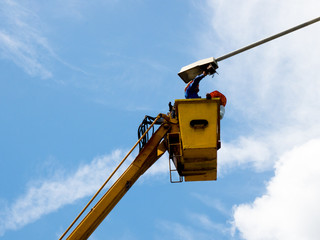Hydraulic lift platform with bucket of yellow construction vehicle, heavy industry, blue sky and white clouds on background
