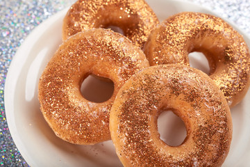 Close-up shot of sweet baked bagels topped with bright shinny glitters and composed on white plate