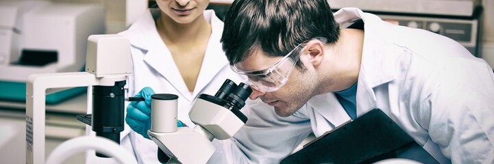 Two scientists observing something with a microscope