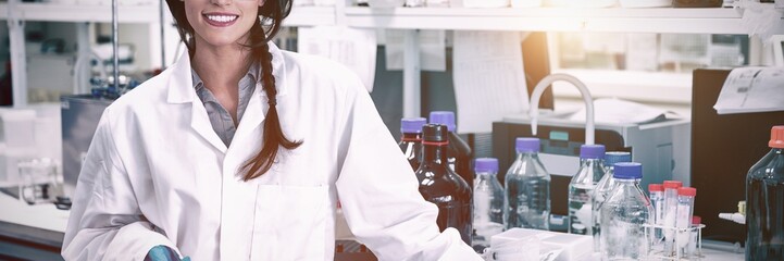 Portrait of a smiling chemist leaning against desk