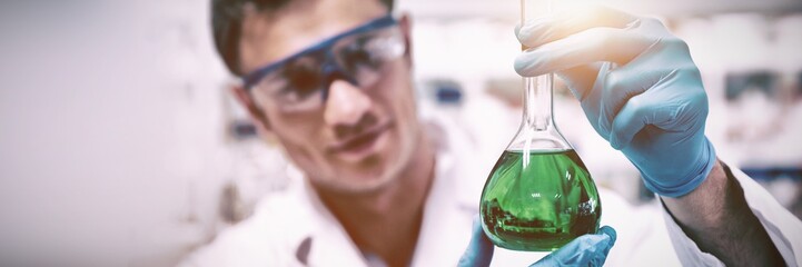 Chemist holding up beaker of green chemical