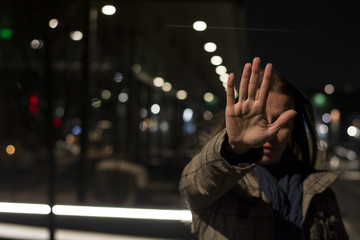Woman showing hand stop sign while standing at night
