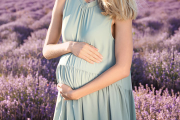Fototapeta na wymiar Pregnant woman in lavender field on summer day