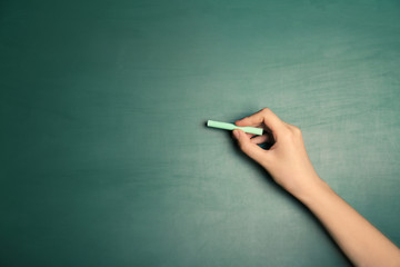 Woman writing with piece of chalk on board
