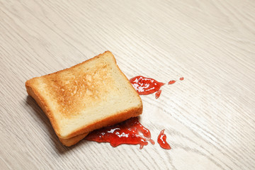 Overturned toast bread with jam on floor