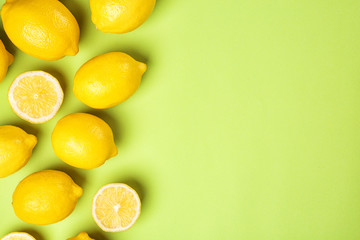 Flat lay composition with whole and sliced lemons on color background