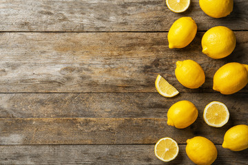 Flat lay composition with whole and sliced lemons on wooden background