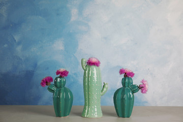 Trendy cactus shaped ceramic vases with flowers on table