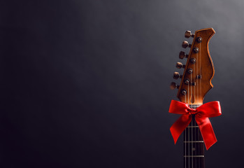 Guitar with bow on black background. Christmas music concept