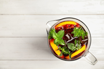 Jug with delicious refreshing cocktail on table, top view