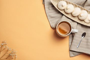 Flat lay composition with cup of tea and meringues on color background