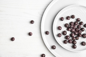 Plates with fresh acai berries on wooden table, top view