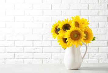 Obraz premium Jug with beautiful yellow sunflowers on table