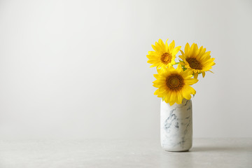 Vase with beautiful yellow sunflowers on table