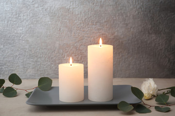 Obraz na płótnie Canvas Candles with floral decor on table against color background