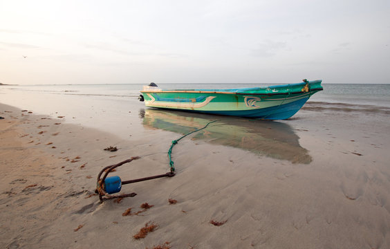 Small fishing boat with anchor at sunset on Nilaveli beach in Trincomalee Sri Lanka Asia