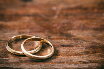 Obraz na płótnie Canvas Two golden wedding rings on wooden background, copy space