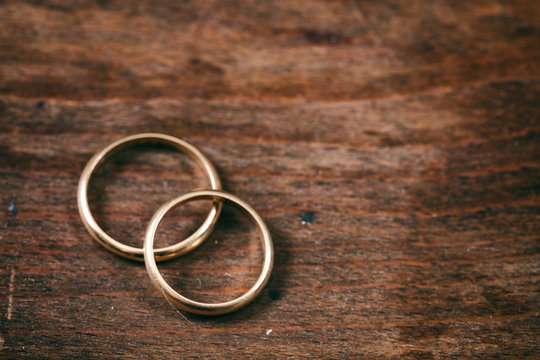 Two golden wedding rings on wooden background, copy space