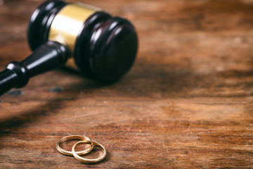 Obraz na płótnie Canvas Wedding rings and judge gavel on wooden background, copy space