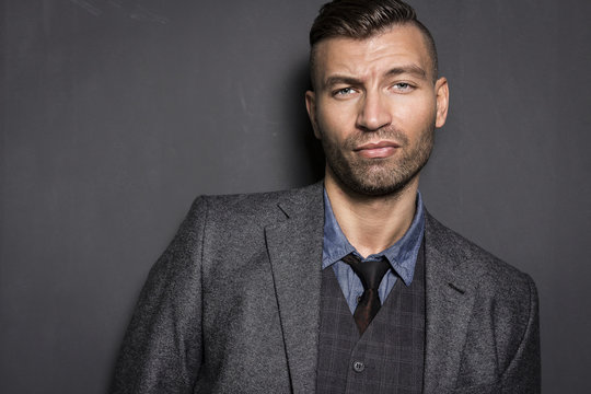 Portrait of stylish, elegant young man in suit with an impudent and prejudiced expression. Brutal young businessman.