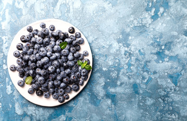 Fresh blueberries on a white plate and blue background. Concept  Healthy Food. Diet Nutrition .Copy space for Text. Top View. Flat Lay.selective focus.