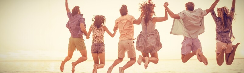 Happy friends holding hands and jumping - obrazy, fototapety, plakaty