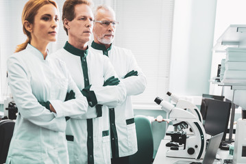Chemical researchers. Three influential chemical researchers standing near modern microscope...