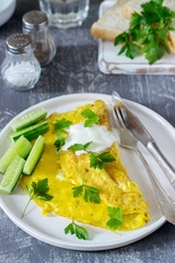 Omelette with parsley, served with sour cream and fresh cucumber.