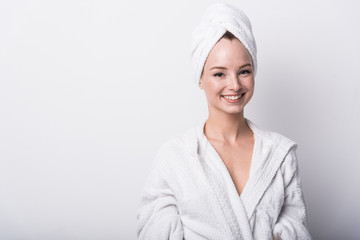  Beautiful red-haired girl in a white bathrobe with a towel on her head on a light background