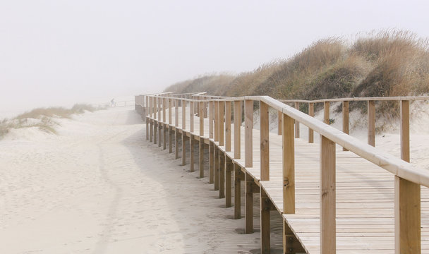 Foggy photo of wooden footbridge of Costa Nova beach in Aveiro, Portugal