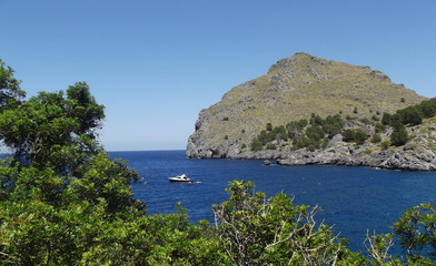 Port de Sa Calobra, view of the ocean with speedboat in water and bright blue sky