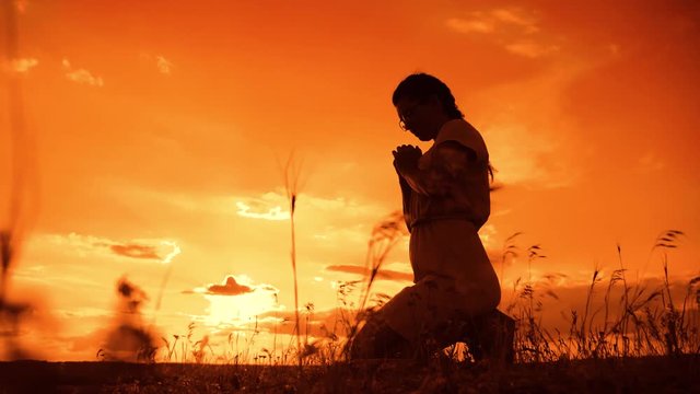 the girl prays. Girl folded her hands in prayer silhouette at sunset. slow motion video. Girl folded her hands in prayer pray to God. girl praying asks forgiveness for sins of repentance. concept