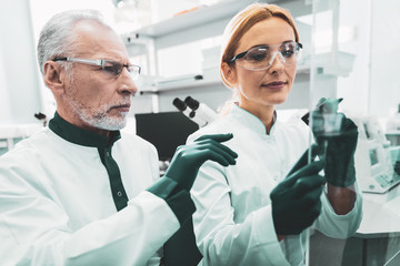 Test tubes. Two busy chemists feeling responsible while holding test tubes in hands sitting in...