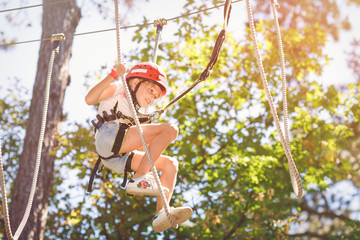 Young girl climbing in forest rope park
