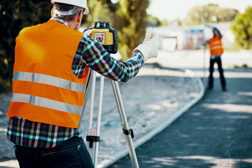 Engineer in reflective vest using equipment during geodetic work