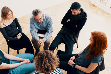 High angle of a group of teenagers sitting in a circle during a psychotherapy