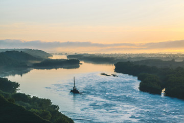 Beautiful river landscape with green shores and ship with copy space. Towboat tows barge with crane...