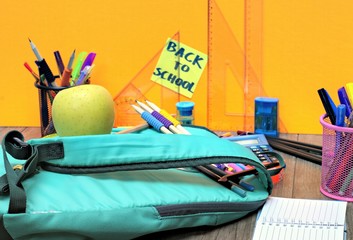  Close-up of a backpack,school tools on an orange background and the inscription back to school.