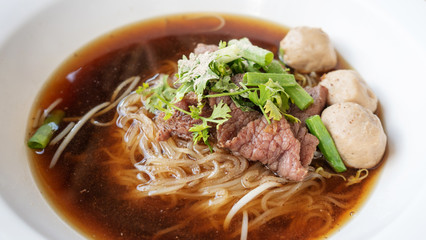 Beef noodles and meatball (Thai style) in a white bowl.