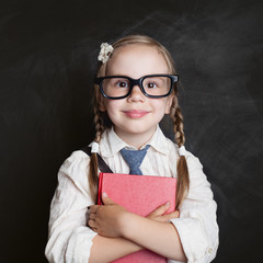 Happy child with book on chalkboard background. Back to school, elementary school lesson and...
