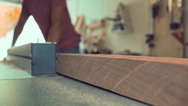 A woodworker using a format saw to cut the hard wood.