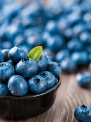 Blueberries in small black bowl on dark tabletop. Shallow DOF. Copy space for text. Vertical.