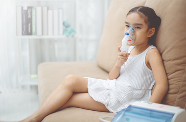Cute Asian child  patient inhalation therapy by the mask of inhaler with soft stream smoke from...