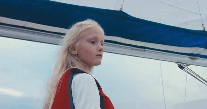 Portrait of cute 6 yo Caucasian girl sailing on yacht on a large lake. 4K UHD 60 FPS SLO MO