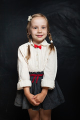 Cute Child on Chalk Board Background. Happy Little Girl in School Uniform. Back to School,...