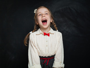 Happy surprised child having fun and laughing on chalk board background. Back to school sale concept