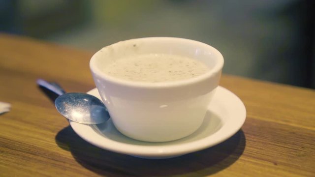 Delicious-looking chicken cream of mushroom soup in a small white bowl on the table in a restaurant
