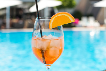 Cold glass of aperol sprit on a pool background