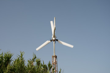 small windmill in movement in with a blue sky