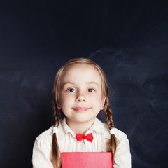 Cheerful little girl portrait. Beautiful child on empty blackboard background with copy space